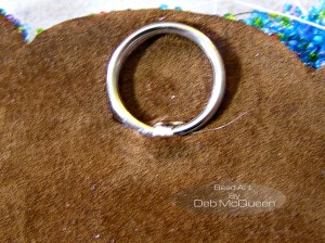 after trimming the beaded felt and cutting a piece of leather for backing I added a ring for hanging